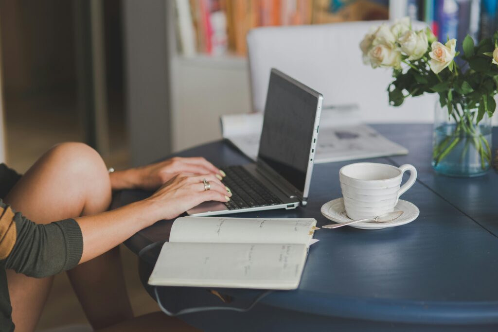 pexels photo 4012966 4012966 Female freelancer using laptop with coffee at home office desk, surrounded by roses and a planner.