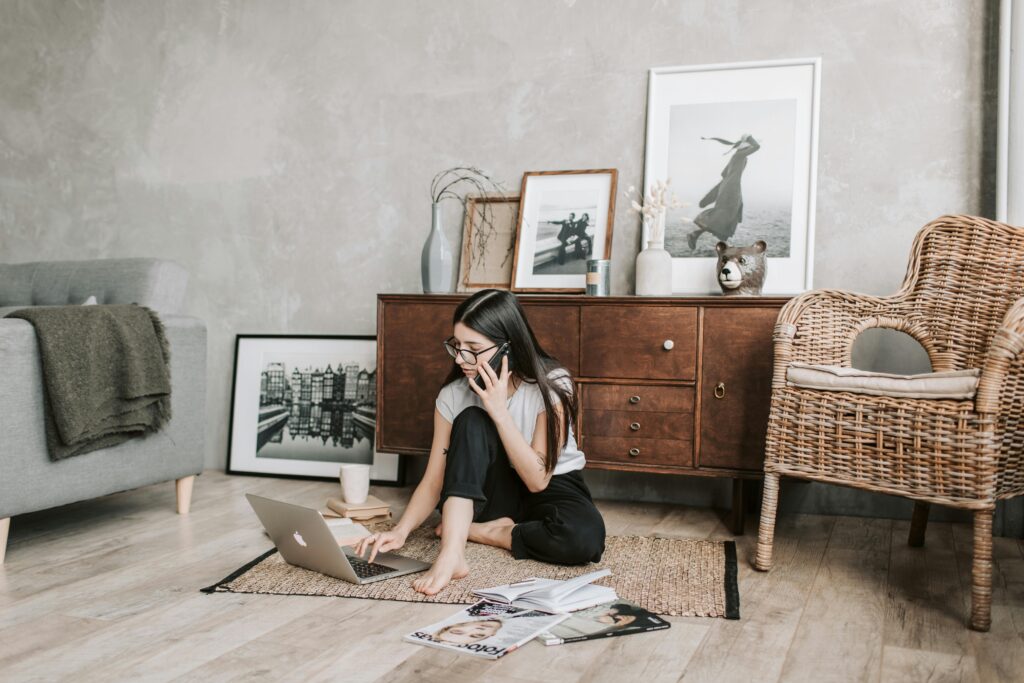 pexels photo 4050321 4050321 Woman using a laptop and phone in a modern, stylish living room with artistic decor.