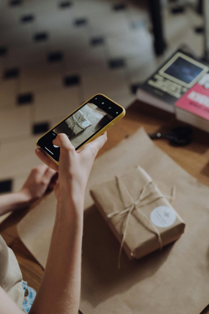 pexels photo 4865729 4865729 A person photographs a wrapped gift with a smartphone indoors.